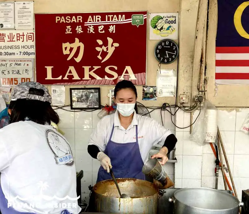 Chinese woman in face-mask Dishing up the famous Penang Laksa Air Itam