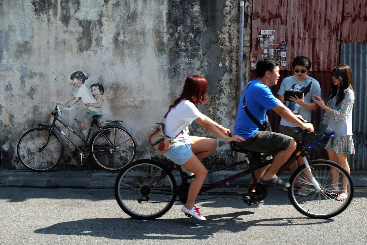 Tourists enjoy a tour of Penang Street Art on a bicycle