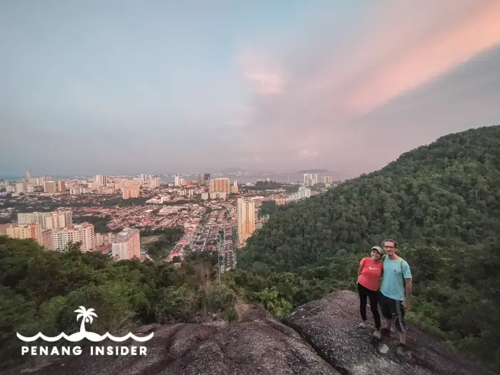 Marco and Kit Yeng stand on top of Bukit Hikau at sunset.
