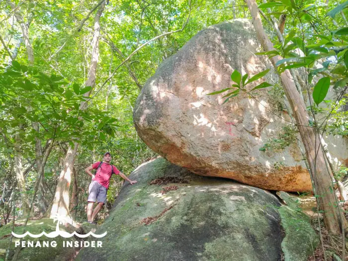 Man next to boulder on the way up Bukit Holland from Yew Bee temple in Penang Bukit Hijau.
